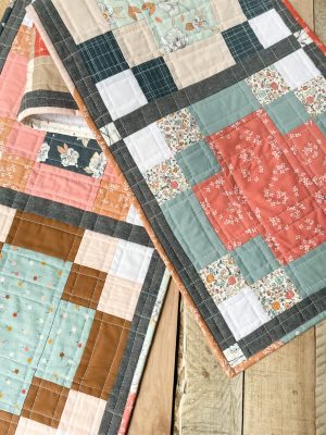 Handcrafted quilts featuring floral and geometric patterns by Heart Lake Quilts, showcasing cozy and colorful designs.