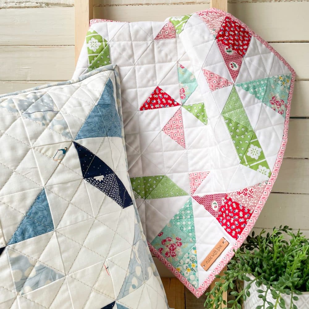 Colorful Heart Lake Quilts designs displayed on a quilted pillow and blanket, showcasing intricate patterns and craftsmanship.