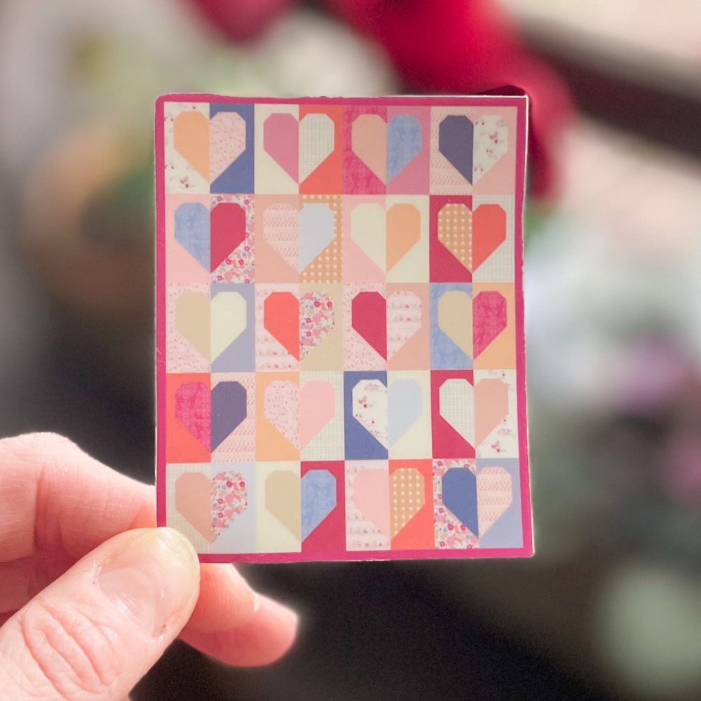 Hand holding colorful heart patchwork card.